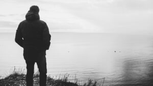 Silhouette of a man facing the ocean horizon, representing the difference between success and a well-lived life, reflection, purpose, and meaning